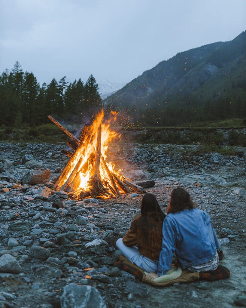 two people sitting by fire