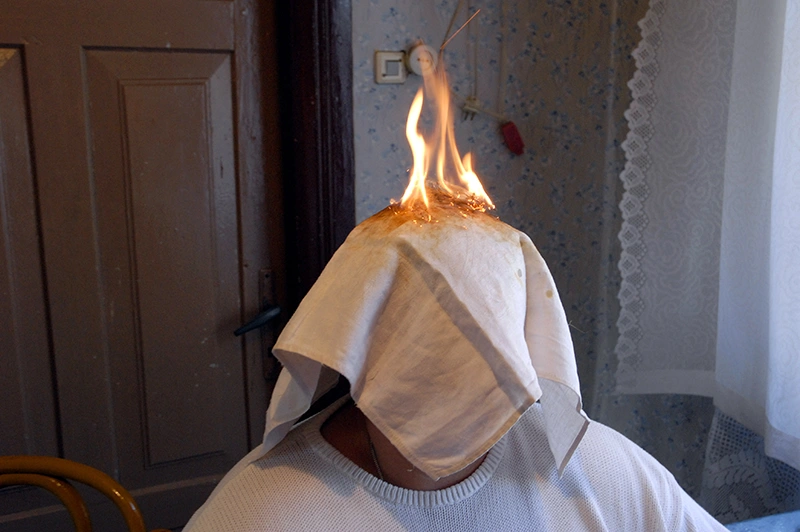 person with burning napkin on head