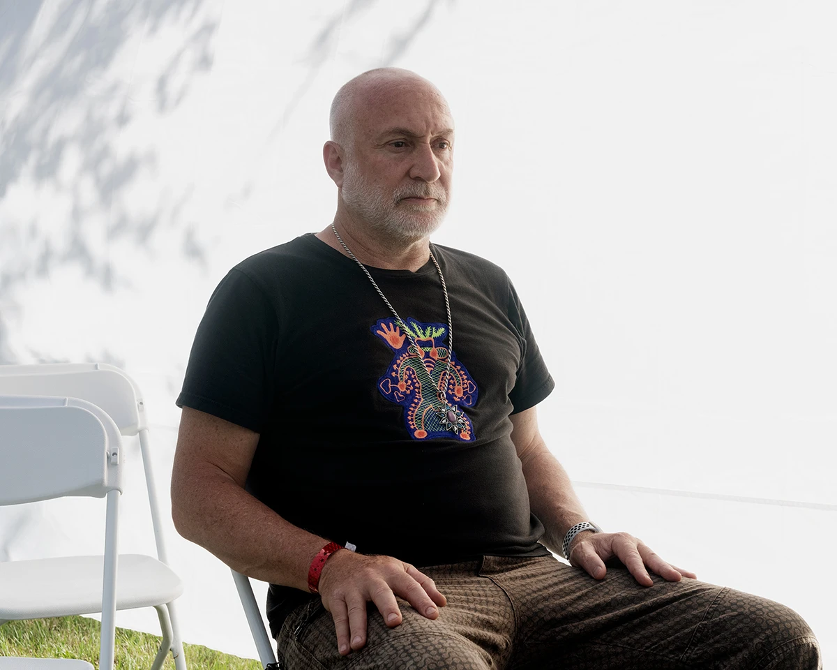 ian benouis, co-founder of the church of psilomethoxin, sits in a chair lost in thought