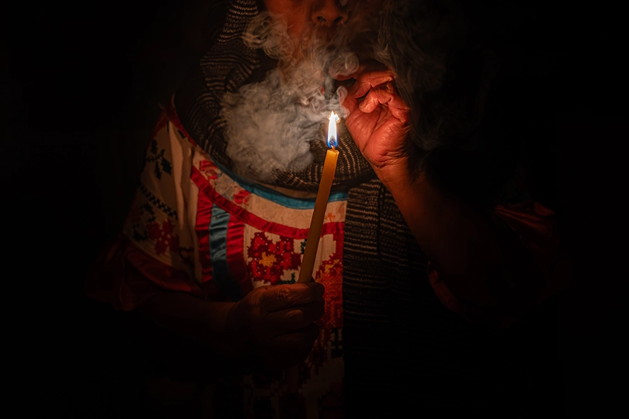 curandera holding candle lighting and smoking scared tobacco