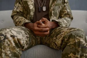 person in army uniform holding hands in lap