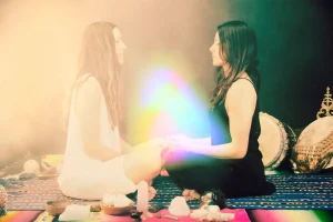 Photo of Two Women Sitting Across from Each Other with Light Orb Between Them